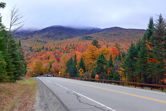 Fototapeta Driving into the mountains with Autumn foliage with red, orange and yellow fall colors in A Northeast forest