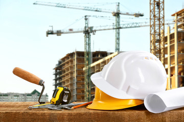 Construction blueprints with tools and helmets on building construction background