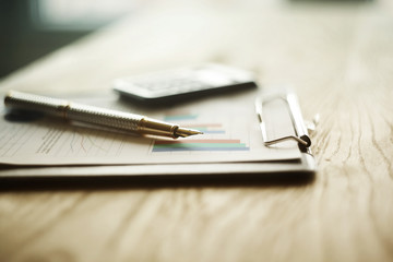 pen, calculator and financial graph on a workplace 