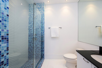 Bathroom with black oval counter-top and blue mosaic glass showe