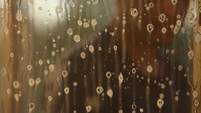 Man sprays soap solution on a window and cleans it (defocused)