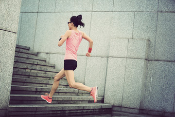 young sport woman running upstairs on city stairs