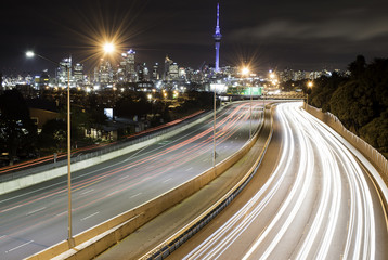 Traffic light trails on the motorway with Auckland CBD in the background