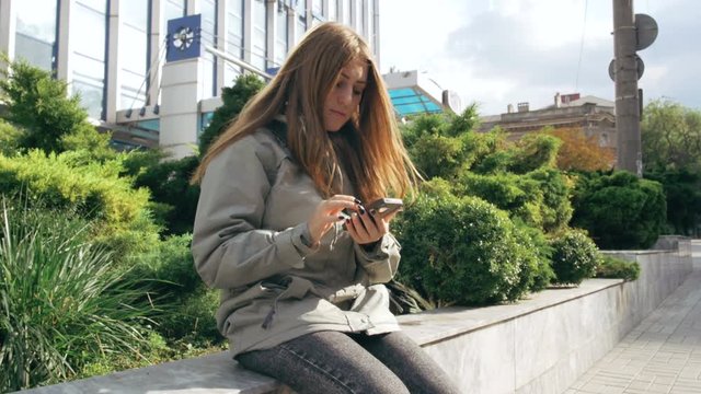 Young attractive female using smartphone in city 