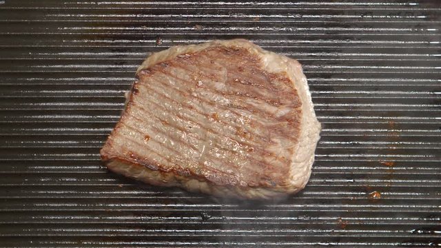TOP VIEW: Tasty beef steak fries on a grill