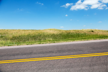 Fototapeta premium A road cutting through grasslands in southern South Dakota on a summer day. 