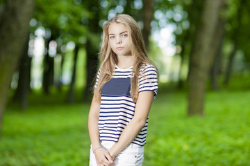 Naklejka na ściany i meble Blond Caucasian Teenager Posing in Green Forest Outdoors.