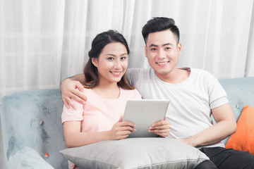 Fototapeta premium Couple at home relaxing on sofa with digital tablet