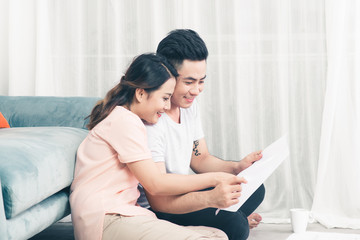 Attractive young asian adult couple looking at house plans.