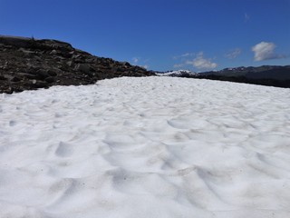 Summer sun heat shrunk a snow field on a hiking trail