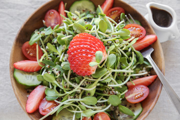 Sunflower sprouts,tomato and strawberries salad on wooden bowl
