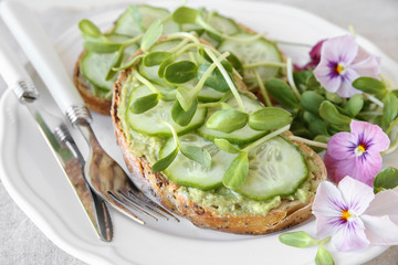 avocado,cucumber,sunflower sprout and edible flowers on sourdough open face sandwiches
