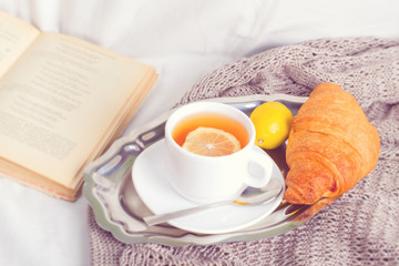 breakfast cup of tea with croissant on a blanket in the bed.toned foto