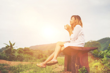 Beautiful young woman holding up a cup of coffee sitting on the
