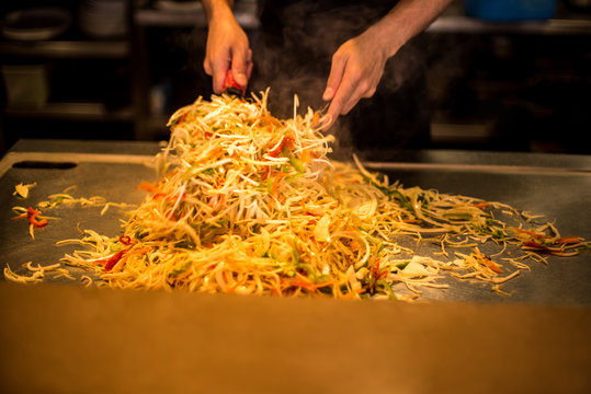 Chef's hands frying noodles with spattle