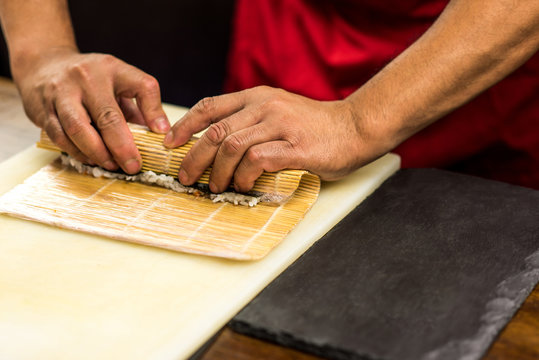 Rooling sushi roll using bomboo mat.