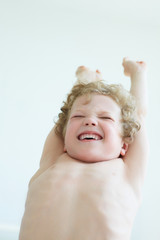 Young boy yawning while stretching arms in bed at home.