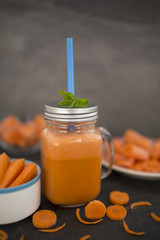 Carrot juice in a mason jar mug on dark stone background. Detox and healthy diet.