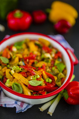 Delicious stewed colored peppers with onions, herbs and spices on dark stone background. Vegetarian food. Healthy diet. 