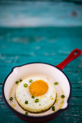 Tasty fried egg in frying pan on old wooden table.  Space for text.