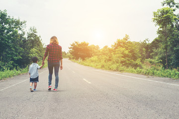 Mother holding a hand of his son in summer day walking on the st