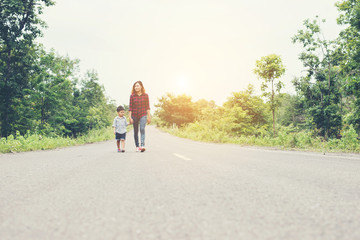 Obraz premium Happy mom holding hand with his son walking on the street.