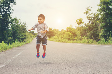 Fototapeta premium Cute little asian boy jumping on the road.