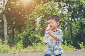 Fototapeta premium Little cute asian boy drink water on the roadside.