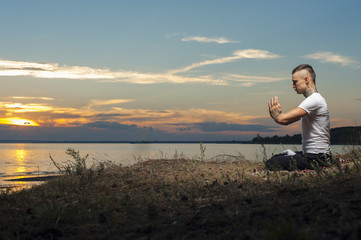 Naklejka na ściany i meble Tattoo man sitting on the beach in yoga meditation pose