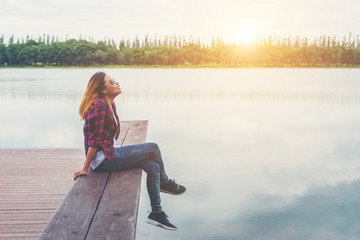 Young beautiful hipster woman sitting on the lake pier ,Relaxed