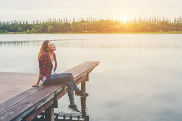 Young beautiful hipster woman sitting on the lake pier ,Relaxed