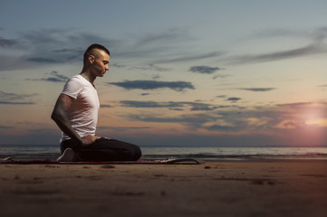 Fototapeta na wymiar Young tattoo man doing yoga exercises on the beach