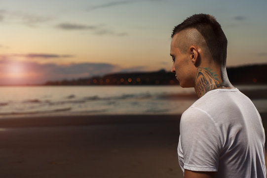 Portrait of young tattoo man meditating on the beach
