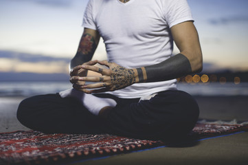 Cropped shot of Man practicing yoga on the beach at sunset