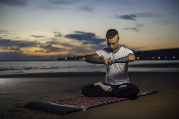Fototapeta premium Flexible young man practicing yoga lotus pose