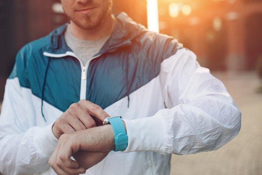 Man tapping the screen of smart watches , sunset on the street