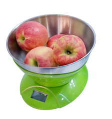 Kitchen electronic scales weigh several red apples.