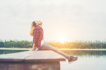 Young hipster woman sitting on wooden pier, Relaxing lying leg d