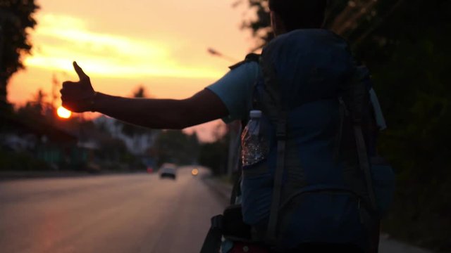 Traveller with Backpack Hitchhiking on Road Travel at Sunset