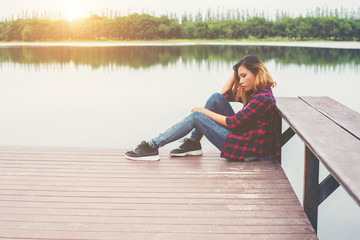 Sad hipster woman sitting on the pier with sadness.