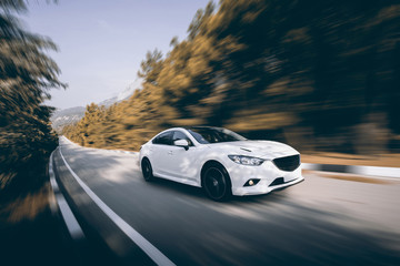 Fototapeta White car speed driving on asphalt road at daytime obraz
