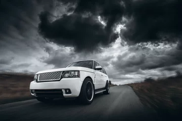 Fotobehang Snelle auto White car speed driving on road at dramatic clouds daytime