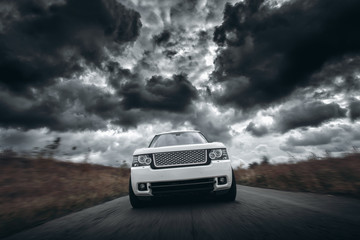 Vitesse de voiture blanche conduite sur route à des nuages dramatiques pendant la journée