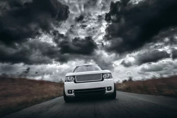 Cercles muraux Voitures rapides Vitesse de voiture blanche conduite sur route à des nuages dramatiques pendant la journée