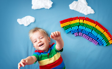 Baby boy lying on the blanket with rainbow and clouds