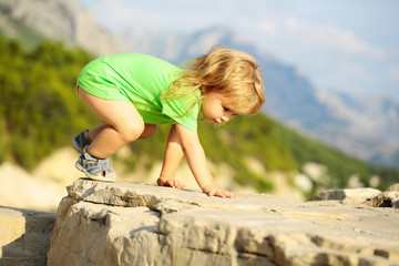 Baby boy plays on rocks