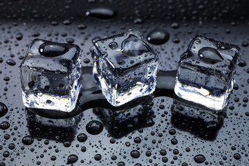 Wet ice cubes and water drop on black background.