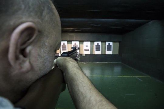 Man aiming with a carbine in an indoor shooting range