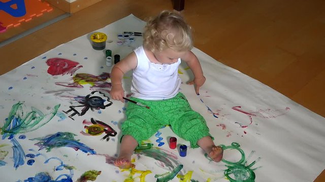 Funny little girl painting on floor at home
