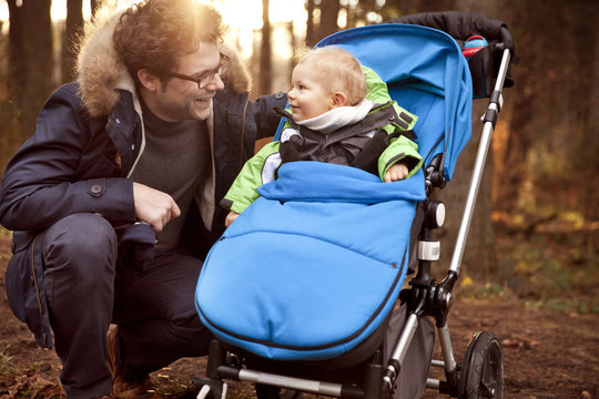 Father smiling at son in buggy in forest